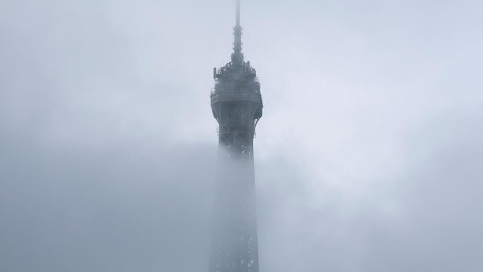 The Eiffel Tower is partially covered by a morning fog in Paris, France, November 16, 2025. REUTERS/Stephanie Lecocq