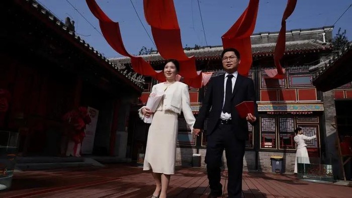 Wang Jieyu, 31, and Zhan Yongqiang, 33, pose for a photographer with their marriage certificates after they registered at the Huguo Guanyin Temple, in Beijing, China October 28, 2025. (Reuters)
