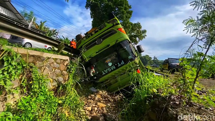 Truk pengangkut batubara terjungkir ke selokan di jalur Cibadak-Warungkiara, Senin (17/11/2025). Warga membantu proses evakuasi sopir dan mengamankan lokasi.