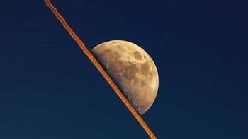 Jejak kondesasi pesawat sejajar sempurna dengan pemandangan Bulan sepotong. Foto: via 121Clicks