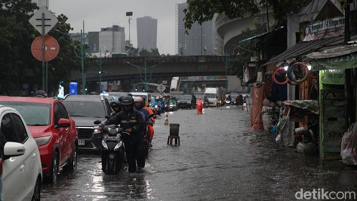 Pengendara menerobos genangan air di Jl Terusan Rasuna Said, Mampang Prapatan, Jakarta Selatan, Selasa (18/11/2025). Hujan deras sejak pukul 11.00 WIB membuat sejumlah ruas jalan tergenang hingga 50 cm.
