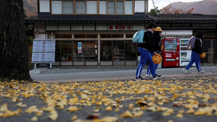 Visitors take souvenir photos next to a bear warning sign at Shirakawa-go, a popular tourist spot and one of Japan's UNESCO World Heritage sites, in Shirakawa village, Gifu Prefecture, Japan, November 15, 2025. REUTERS/Issei Kato
