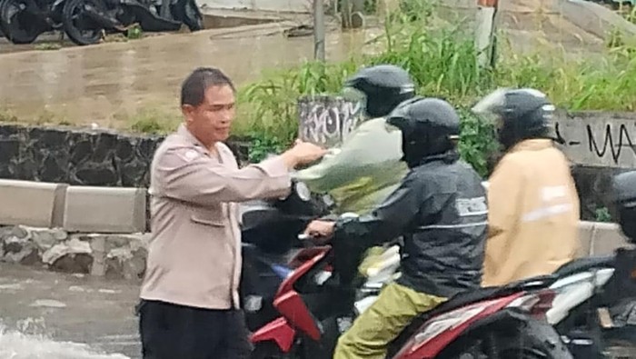 Polisi melakukan pengaturan lalu lintas di Jalan Aria Putra, Ciputat yang sempat tergenang banjir, Selasa (18/11/2025).