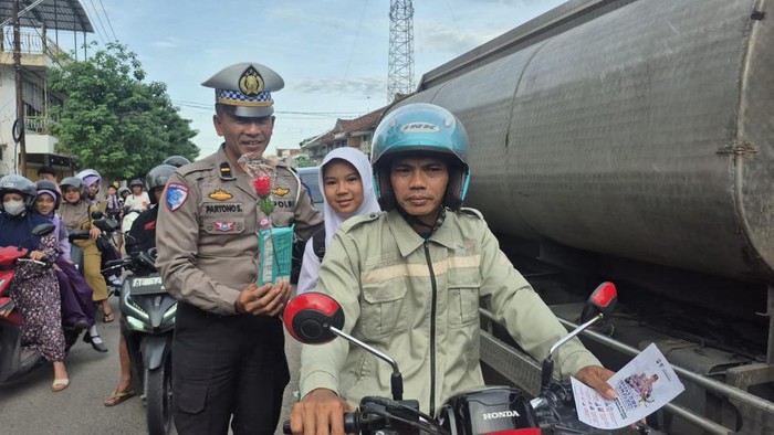 Polisi saat membagikan bunga dan jajan kepada pengendara