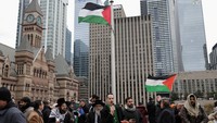 Bentangan bendera Palestina terlihat jelas dari kejauhan, berkibar di antara gedung-gedung tinggi Toronto. Ribuan warga berkumpul di area Balai Kota, mengibarkan bendera Palestina sambil membawa spanduk berisi pesan solidaritas. REUTERS/Wa Lone