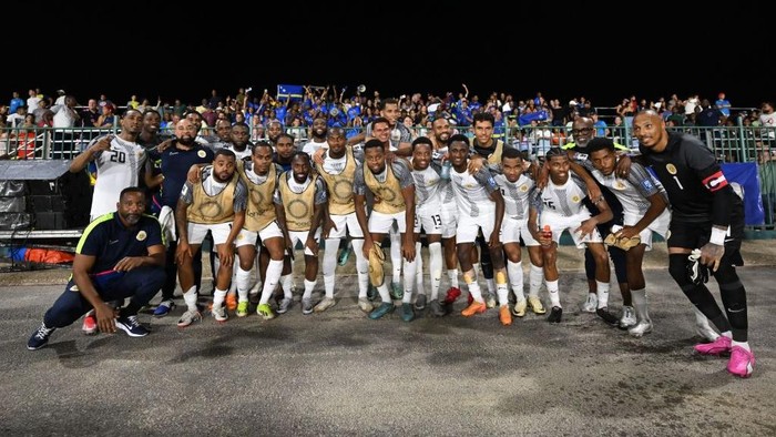 [UNVERIFIED CONTENT] View from the top of the cliffs at Lagun Beach towards the  beach, Curacao, Netherland Antilles.

A couple of persons can be seen walking towards the Caribbeans pristine and turquoise water. Also, it can be seen some colorful fisherman boats on the left side of picture.

The rocky cliffs and a partially cloudy sky can be seen at the background.