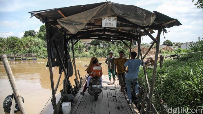 Perahu eretan membawa penumpang menyebrangi sungai CBL di perbatasan Desa Sukawangi dan Desa Kedung Pengawas, Kecamatan Babelan, Kabupaten Bekasi Jawa Barat, Rabu (19/11/2025).