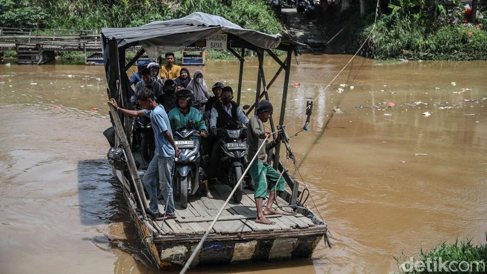 Perahu eretan membawa penumpang menyebrangi sungai CBL di perbatasan Desa Sukawangi dan Desa Kedung Pengawas, Kecamatan Babelan, Kabupaten Bekasi Jawa Barat, Rabu (19/11/2025).