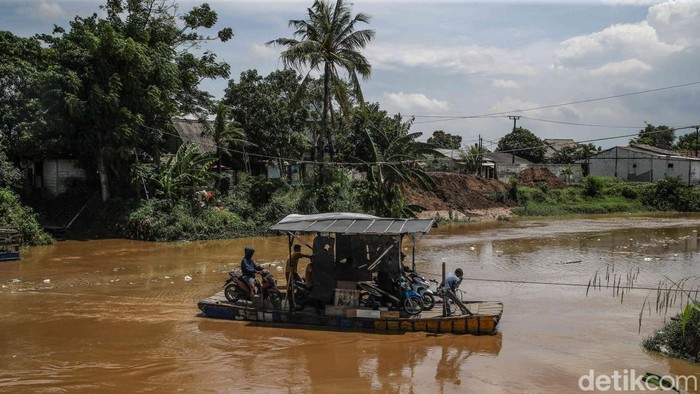 Perahu eretan membawa penumpang menyebrangi sungai CBL di perbatasan Desa Sukawangi dan Desa Kedung Pengawas, Kecamatan Babelan, Kabupaten Bekasi Jawa Barat, Rabu (19/11/2025).