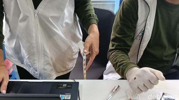 Petugas tengah mengecek hasil pengukuran lingkar perut di tenda cek kesehatan gratis MRT Blok M.