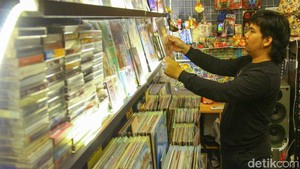 Seorang pekerja saat merapihkan piringan hitam yang dijual di Pasar Santa, Jakarta.