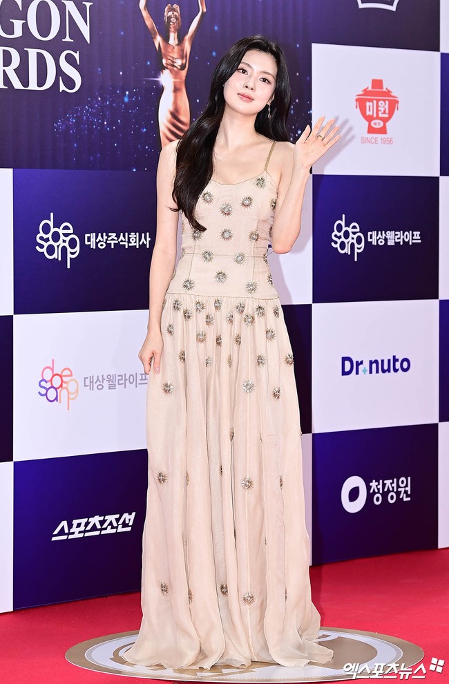 Kekasih Lee Kwang Soo, Lee Sun Bin viral karena aksi jenakanya saat melihat sang aktor membacakan nominasi di atas panggung, sampai salah tingkah. Hadir dalam balutan gaun berwarna krem, didominasi detail print matahari. Foto: dok. Xports News