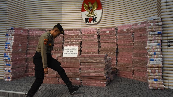 Polisi menjaga tumpukan uang yang merupakan barang rampasan negara saat acara penyerahan barang rampasan negara dari KPK kepada PT TASPEN di Gedung Merah Putih KPK, Jakarta, Kamis (20/11/2025). PT TASPEN (Persero) menerima secara resmi pengembalian kerugian keuangan negara berupa Unit Penyertaan Reksa Dana Insight Tunas Bangsa Balanced Fund 2 (I-Next G2) dengan jumlah unit 996.694.959,5143 senilai Rp883.038.394.268 dari KPK, di mana dana restitusi tersebut merupakan hasil tindak lanjut proses hukum terkait kasus dugaan investasi fiktif sekaligus menjadi langkah penting dalam upaya pemulihan aset negara dan perlindungan dana peserta TASPEN. ANTARA FOTO/Indrianto Eko Suwarso/tom.
