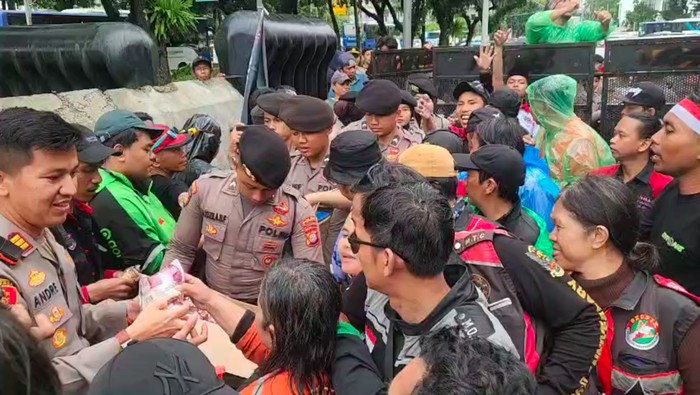 Personel Polda Metro Jaya mengamankan demo dari pelaku transportasi online. Polisi juga menunjukkan kepedulian dengan membagikan makan dan minuman ke massa. (dok Istimewa)