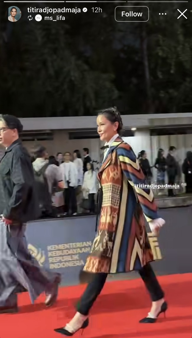 Penampilan Titi Rajo tak kalah jadi sorotan. Ia mengenakan outer etnik oversized yang dipadukan dengan celana panjang hitam serta high heels dan dasi kupu-kupu. Foto: Instagram
