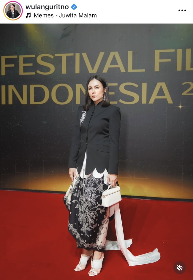 Wulan Guritno mengenakan blazer hitam dipadukan dengan rok motif floral bernuansa hitam putih. Ia juga terlihat membawa handbag putih. Foto: Instagram