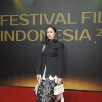 Wulan Guritno mengenakan blazer hitam dipadukan dengan rok motif floral bernuansa hitam putih. Ia juga terlihat membawa handbag putih. Foto: Instagram