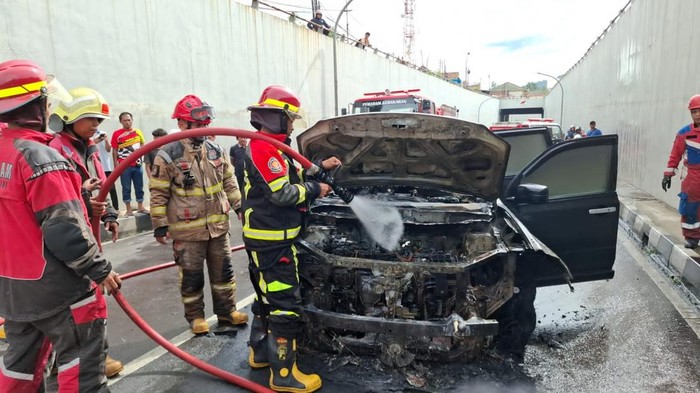 Personel Damkar Cimahi memadamkan api yang membakar mobil di Underpass Dustira