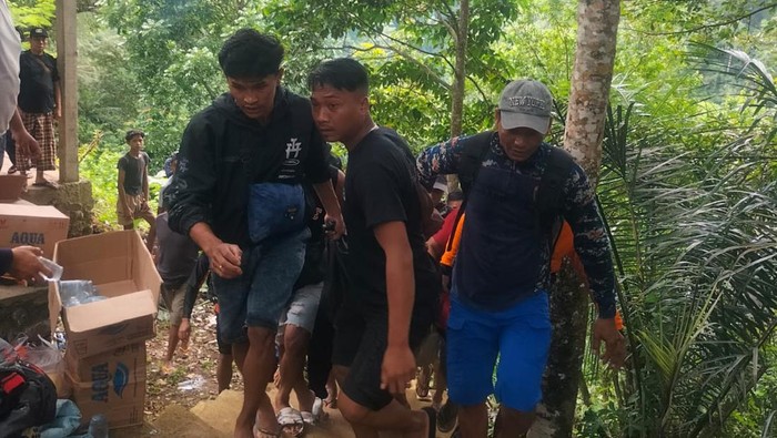 Petugas dan warga menggotong pria yang jatuh dari tebing saat menyaksikan proses evakuasi korban tenggelam di Air Terjun Kebo Iwa, Buleleng, Jumat (21/11/2025).