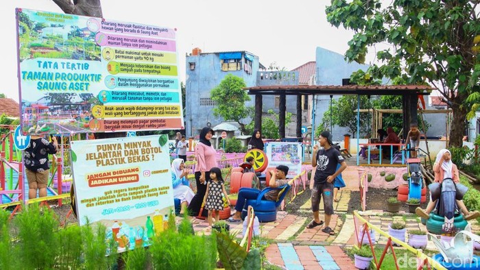 Warga melintas di area Taman Produktif Saung Aset yang kini menjadi ruang hijau baru di Batu Ampar, Kramat Jati, Jakarta, Jumat (21/11/2025). Ruang terbuka ini lahir dari lahan bekas pembuangan sampah yang disulap menjadi taman edukasi urban farming.