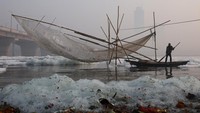 Seorang nelayan menatap aliran sungai yang nyaris tertutup busa kimia, simbol kerusakan ekologis yang semakin sulit dikendalikan di New Delhi. REUTERS/Bhawika Chhabra