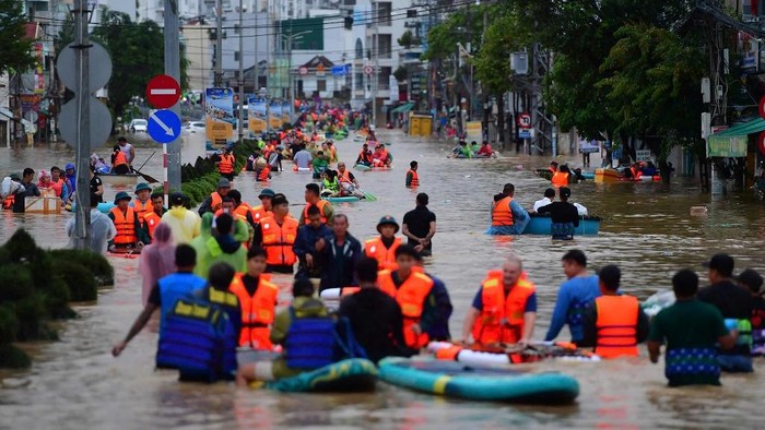 This photo taken on November 20, 2025 shows people wading through floodwaters in Nha Trang in Vietnams coastal province of Khanh Hoa. Rescuers raced to find more than a dozen people still missing on November 22 after a week of heavy flooding in Vietnam, where authorities said at least 55 people have died. (Photo by Duc Thao / AFP)