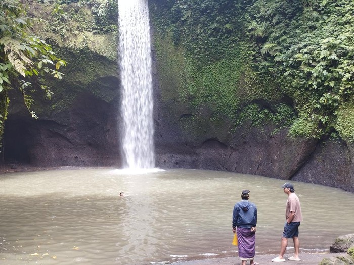 Seorang penjaga Air Terjun Tibumana tengah mengobrol dengan pengunjung, Sabtu (15/11/2025). Gerojokan tersebut dijaga oleh empat petugas untuk mencegah pelancong tenggelam.
