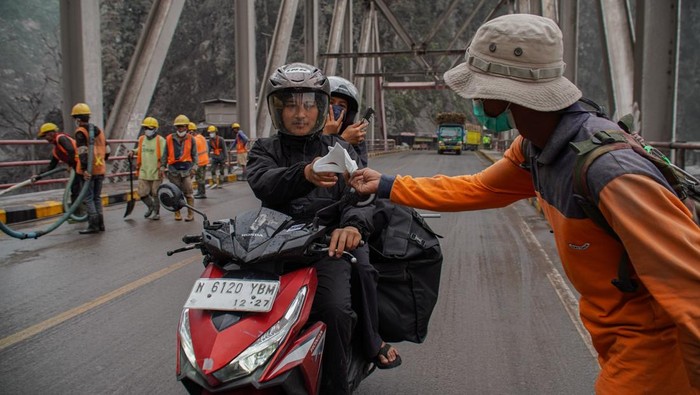 Relawan membagikan masker kepada warga di Lumajang, Jawa Timur, Sabtu (22/11/2025). Pembagian masker gratis kepada warga tersebut untuk upaya perlindungan diri dari paparan abu vulkanik akibat aktivitas erupsi Gunung Semeru. ANTARA FOTO/Irfan Sumanjaya/rwa.