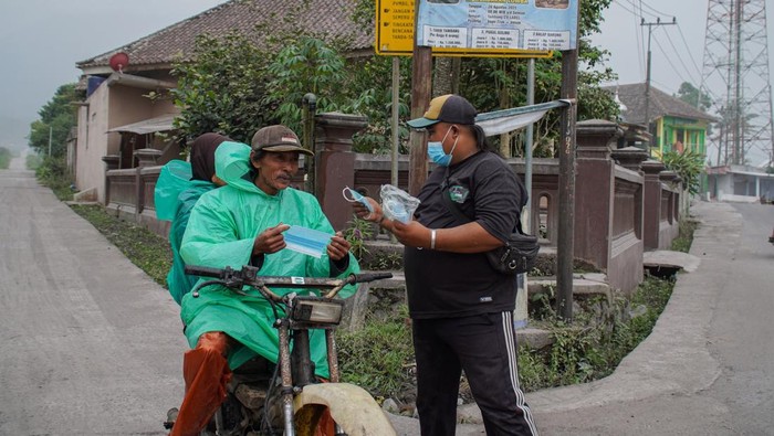 Relawan membagikan masker kepada warga di Lumajang, Jawa Timur, Sabtu (22/11/2025). Pembagian masker gratis kepada warga tersebut untuk upaya perlindungan diri dari paparan abu vulkanik akibat aktivitas erupsi Gunung Semeru. ANTARA FOTO/Irfan Sumanjaya/rwa.