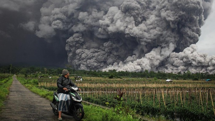 Warga melihat luncuran awan panas Gunung Semeru di Lumajang, Jawa Timur, Rabu (19/11/2025). Sebanyak tiga orang warga mengalami luka bakar dan dirawat di RSUD dr Haryoto Lumajang akibat bencana erupsi Gunung Semeru. (Photo by Agus Harianto / AFP)