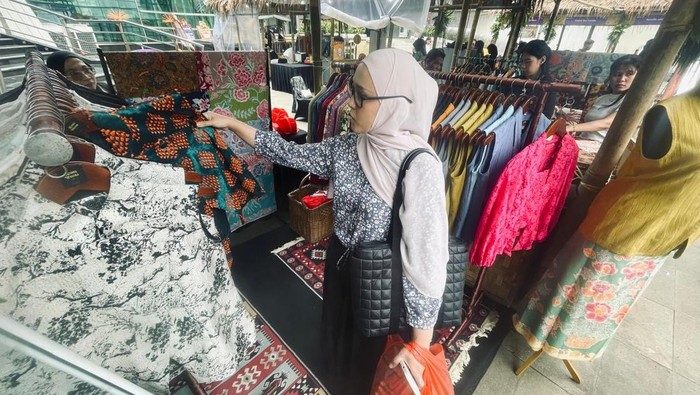 Pengunjung mengamati beragam busana produk UMKM yang dipamerkan pada Ruang Lestari Amartha Impact Festival 2025 di Taman Ismail Marzuki, Jakarta, Minggu (23/11/2025).