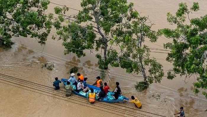 This aerial photo shows people wading through floodwaters in Phan Rang in southern Vietnams Khanh Hoa province on November 21, 2025. Rescuers raced to find more than a dozen people still missing on November 22 after a week of heavy flooding in Vietnam, where authorities said at least 55 people have died. (Photo by Bao Quan / AFP)