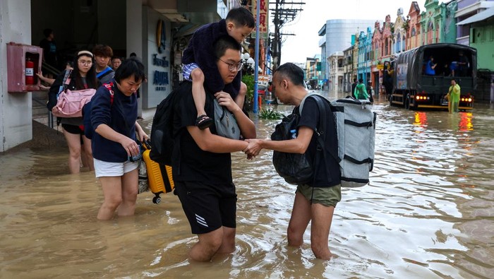 People stand in water in a flooded area in Hat Yai district, Songkhla, Thailand, November 23, 2025. REUTERS/Roylee Suriyaworakul