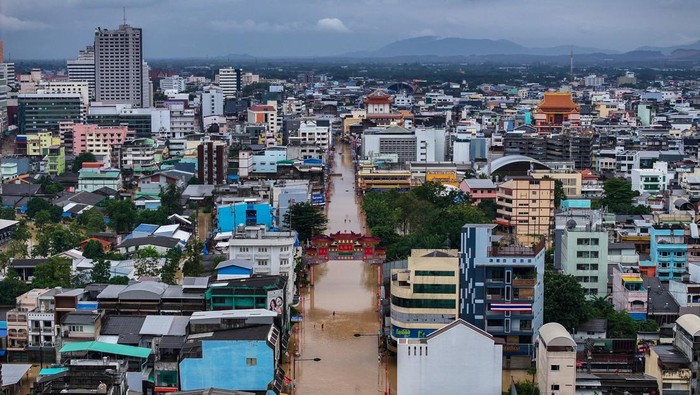 People stand in water in a flooded area in Hat Yai district, Songkhla, Thailand, November 23, 2025. REUTERS/Roylee Suriyaworakul