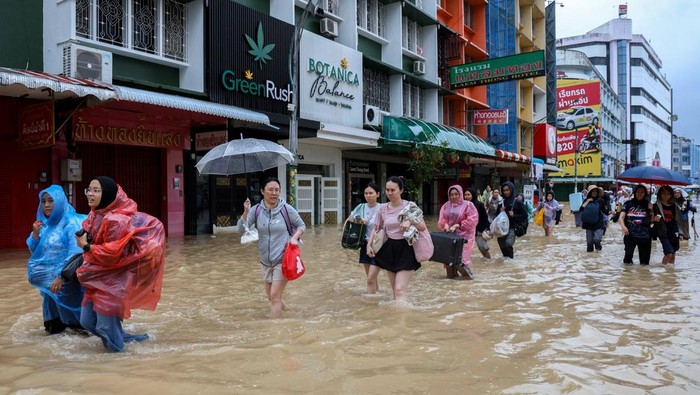 People stand in water in a flooded area in Hat Yai district, Songkhla, Thailand, November 23, 2025. REUTERS/Roylee Suriyaworakul