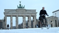 Tak jauh berbeda, kawasan Gerbang Brandenburg—salah satu landmark paling terkenal di Berlin—juga dipenuhi pemandangan serupa. Orang-orang bersepeda melintasi jalanan yang basah oleh salju, tetap menjalankan aktivitas harian meski suhu udara menurun drastis. Kontras antara bangunan bersejarah dan hamparan salju menciptakan panorama musim dingin yang memukau. REUTERS/Annegret Hilse