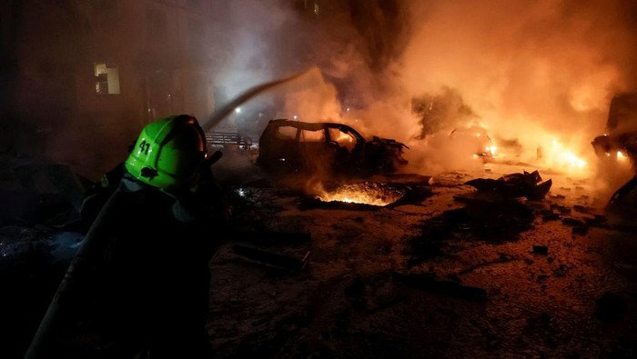 A firefighter puts out the fire in burning cars near the apartment building hit by a Russian drone strike, amid Russia's attack on Ukraine, in Kharkiv, Ukraine November 19, 2025. REUTERS/Sofiia Gatilova
