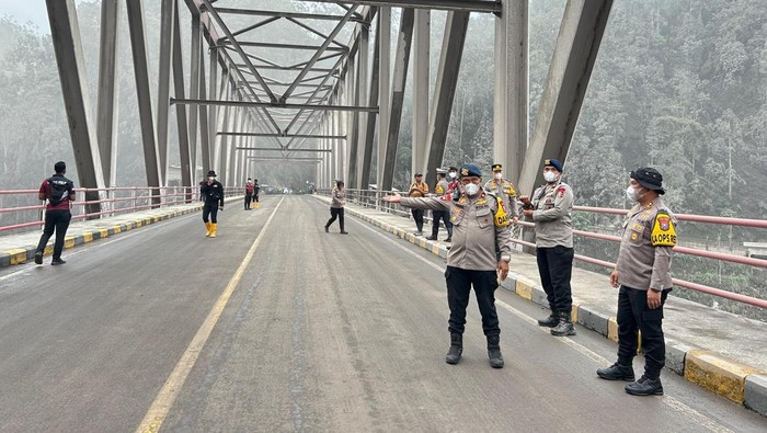 Personel kepolisian dari Polda Jatim yang bersiaga di Jembatan Besuk Kobokan atau Gladak Perak mengatur lalu lintas buka tutup seiring terjadinya letusan sekunder Semeru.