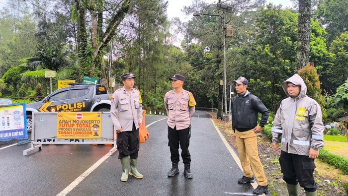 Petugas kepolisian melakukan penutupan akses jalur pacet-cangar karena ada longsor.