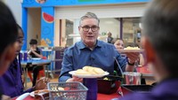 Perdana Menteri Inggris Keir Starmer membantu menyajikan makan siang saat berkunjung ke Welland Academy untuk membahas pentingnya makanan sekolah gratis dan mengatasi biaya hidup di Peterborough, Cambridgeshire, Inggris, Senin (24/11/2025). REUTERS/Joe Giddens