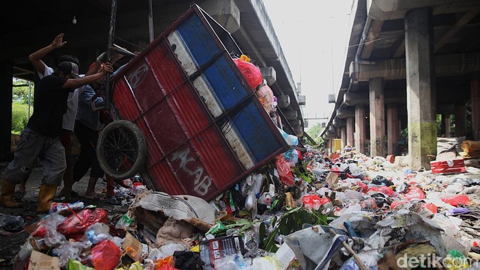 Pekerja beraktivitas di tempat pembuangan sementara (TPS) sampah di kolong Tol Wiyoto Wiyono, Sungai Bambu, Tanjung Priok, Jakarta Utara, Senin, (24/11/2025). Warga sekitar mengeluhkan kehadiran TPS tersebut karena kenaikan volume sampah dari hari ke hari menyebabkan bau tak sedap dan kualitas lingkungan menurun. Status TPS tersebut juga masih kontroversial karena tidak diperkenankan ada bangunan atau aktivitas permanen di kolong tol.