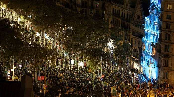 Local and tourists use their mobile phones to record the spectacle over the facade of the Casa Batllo, designed by Catalan architect Antoni Gaudi, during the switching on of Christmas lights at Passeig de Gracia, marking the start of the festive season in Barcelona, Spain November 22, 2025. REUTERS/Nacho Doce