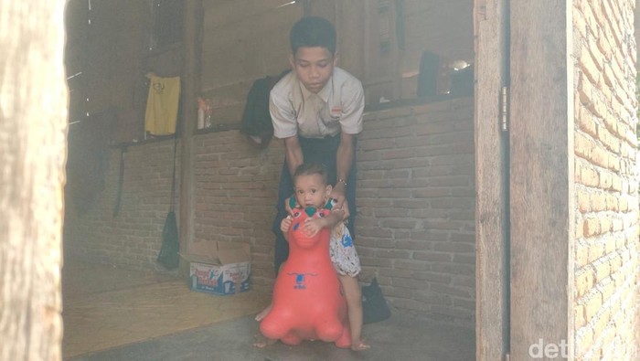 Siswa SMP di Polman, Muhammad Supri (15) menggendong adiknya yang sempat dibawa ke sekolah.