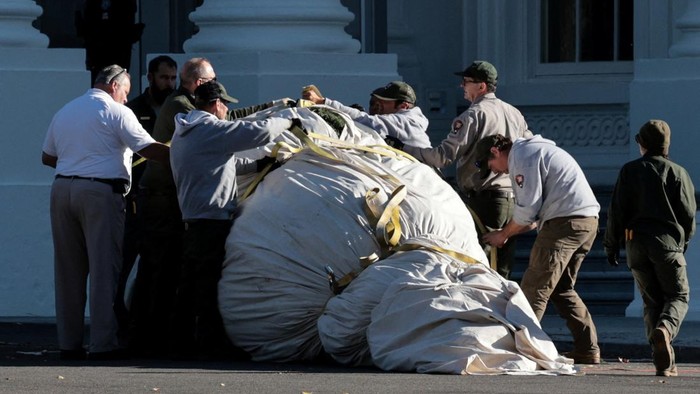 Workers wrap the White House Christmas tree in a tarp before moving it inside to decorate, in Washington, D.C., U.S., November 24, 2025. REUTERS/Jonathan Ernst