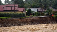 Warga berada di tepi jalan penghubung antar desa yang longsor akibat luapan sungai di Nagari Salibutan, Lubuk Alung, Padang Pariaman, Sumatera Barat. ANTARA FOTO/Iggoy el Fitra