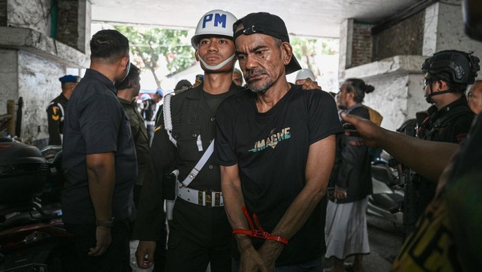 Petugas membawa anjing K9 saat penggerebekan lokasi yang diduga menjadi tempat peredaran narkoba di Kampung Berlan, Matraman, Jakarta, Selasa (25/11/2025). Badan Narkotika Nasional (BNN) bersama Puspom TNI AD dan Bareskrim Polri melakukan operasi pemulihan kampung narkoba yang melibatkan 450 orang personil dengan mengamankan 23 tersangka dan barang bukti diantaranya sabu dan senjata api. ANTARA FOTO/Fauzan