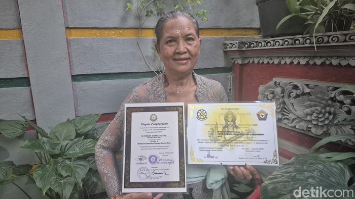 Potret Ni Nyoman Marsithi memegang piagam penghargaannya.