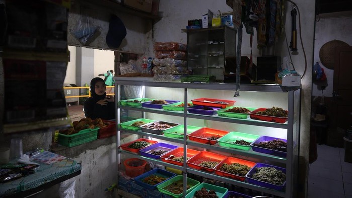 Pekerja membeli makanan dan minuman melalui lubang yang dibuat pedagang pada tembok pembatas salah satu pusat perbelanjaan dengan permukiman di Kemang, Jakarta, Selasa (25/11/2025). Pedagang makanan di lokasi tersebut membuat lubang di tembok sebagai akses alternatif bagi pelanggan yang merupakan karyawan di pertokoan dan perkantoran sekitar agar bisa lebih praktis dan menghemat waktu saat membeli makanan dan minuman di kedai mereka. ANTARAFOTO/Muhammad Rizky Febriansyah