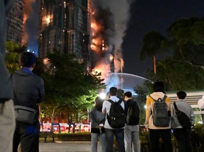 Firefighters spray water during a major fire at the Wang Fuk Court residential estate in Hong Kongs Tai Po district on November 26, 2025. At least four people were killed when a fire engulfed several high-rise blocks in a Hong Kong residential estate on November 26, the government said, with media reporting that some residents were trapped inside. (Photo by Peter PARKS / AFP)