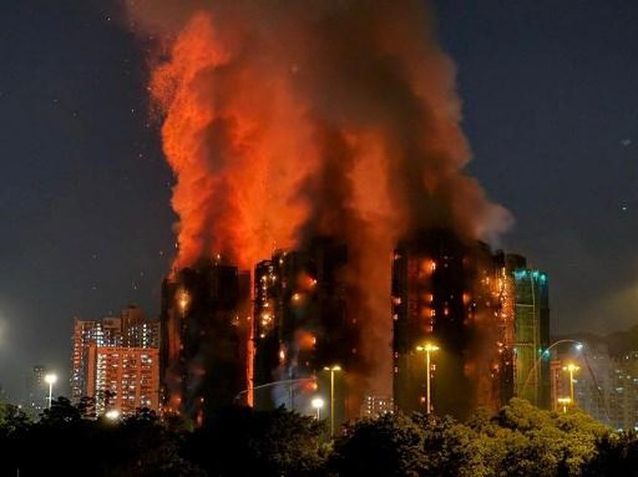 Thick smoke and flames rise as a major fire engulfs several apartment blocks at the Wang Fuk Court residential estate in Hong Kongs Tai Po district on November 26, 2025. At least four people were killed when a fire engulfed several high-rise blocks in a Hong Kong residential estate on November 26, the government said, with media reporting that some residents were trapped inside. (Photo by Yan ZHAO / AFP)